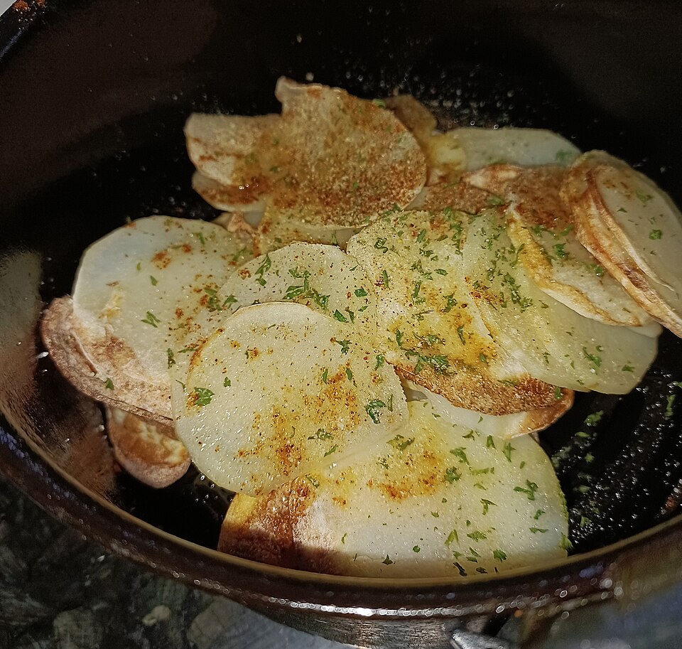 Thin potato slices arranged inside an air fryer, shown as an illustrative example