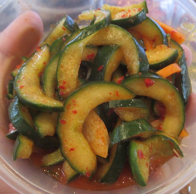 Bright Korean spicy cucumber slices with sesame and red pepper in a dish; illustrative oi-muchim recipe photo
