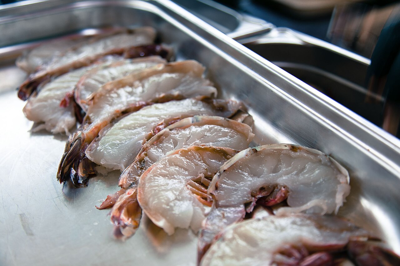 Raw shrimp split open before cooking, illustrating seafood preparation, not the breading process itself